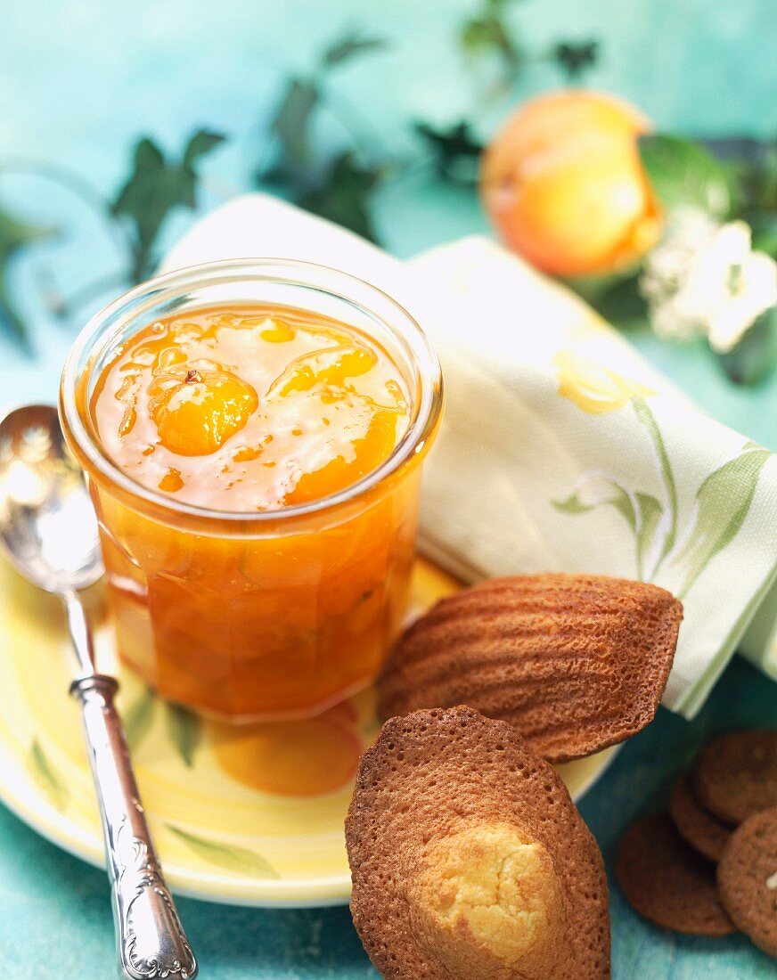 Pot of citrus fruit jam with madeleine cakes