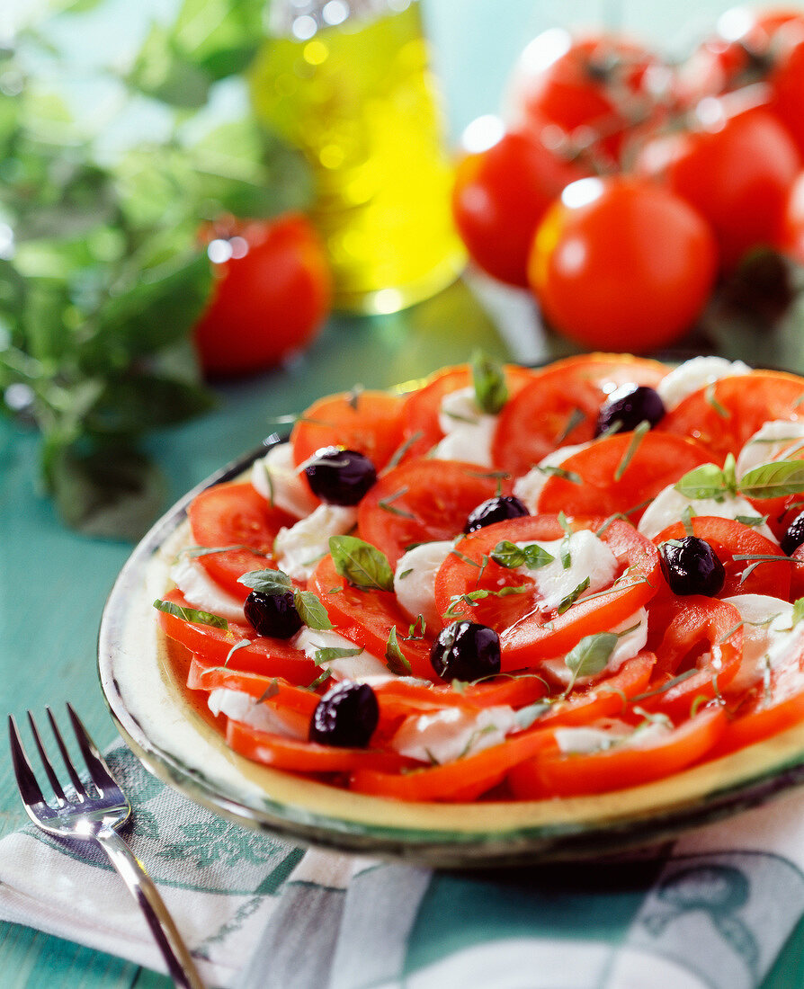 Tomate-Mozzarella-Salat mit schwarzen Oliven und Basilikum