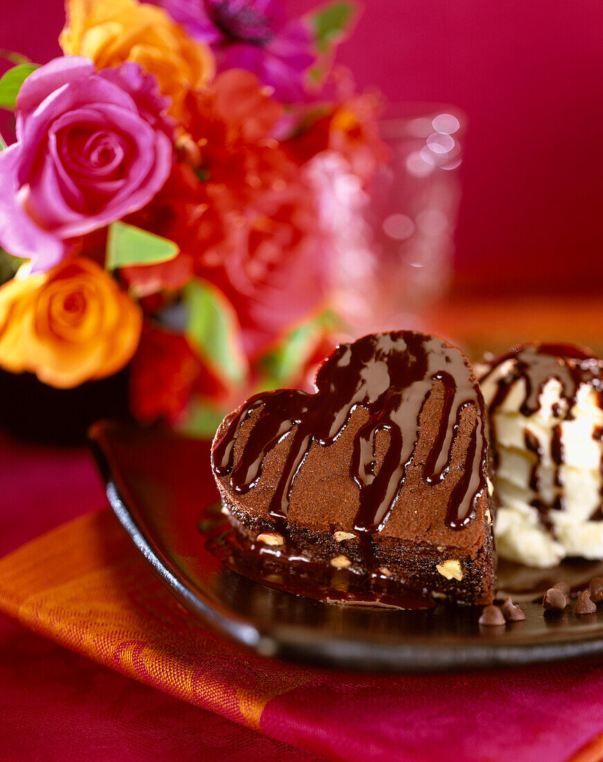 Herz-Brownie und Schlagsahne mit Schokoladensauce und Blumendeko