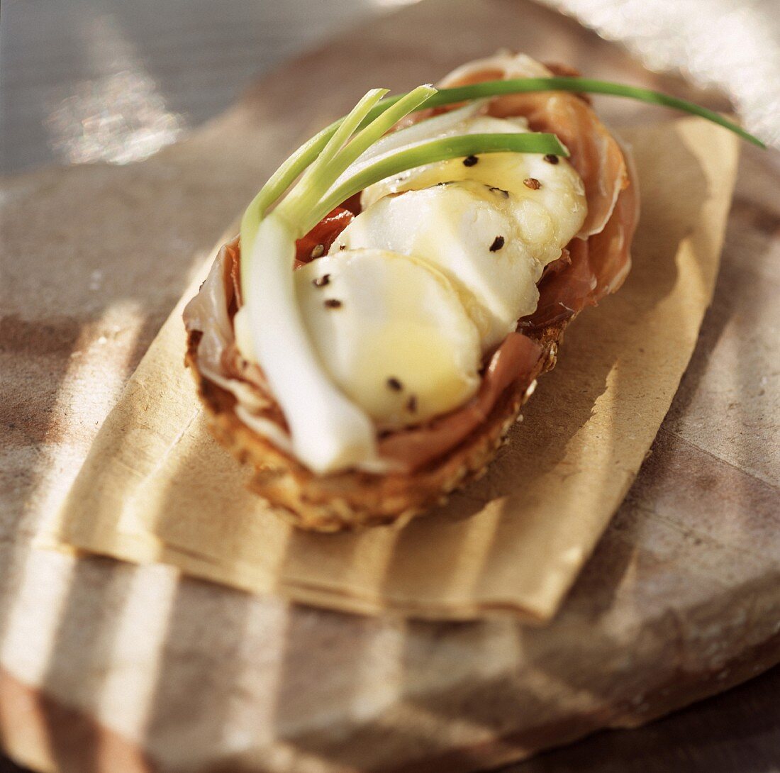 Warmer Ziegenkäse und Parmaschinken auf Brotscheibe