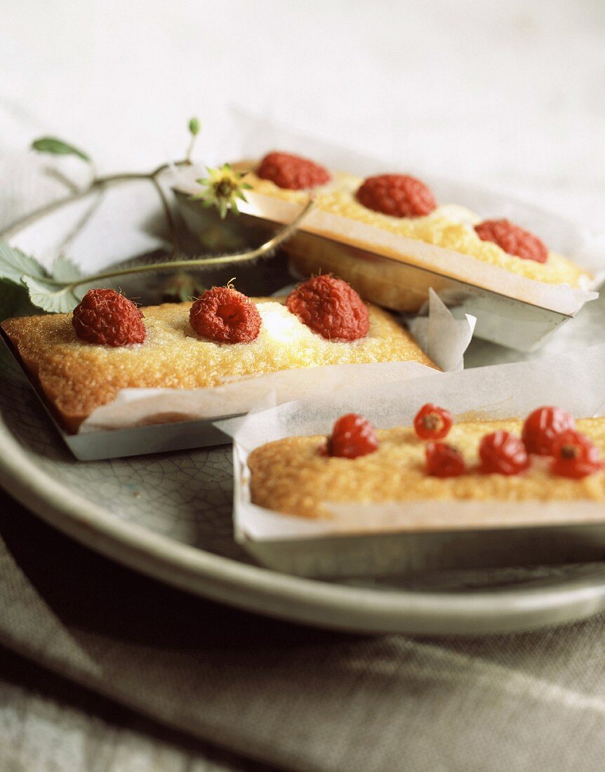 Financiers (französisches Mandelgebäck) mit Himbeeren und roten Johannisbeeren