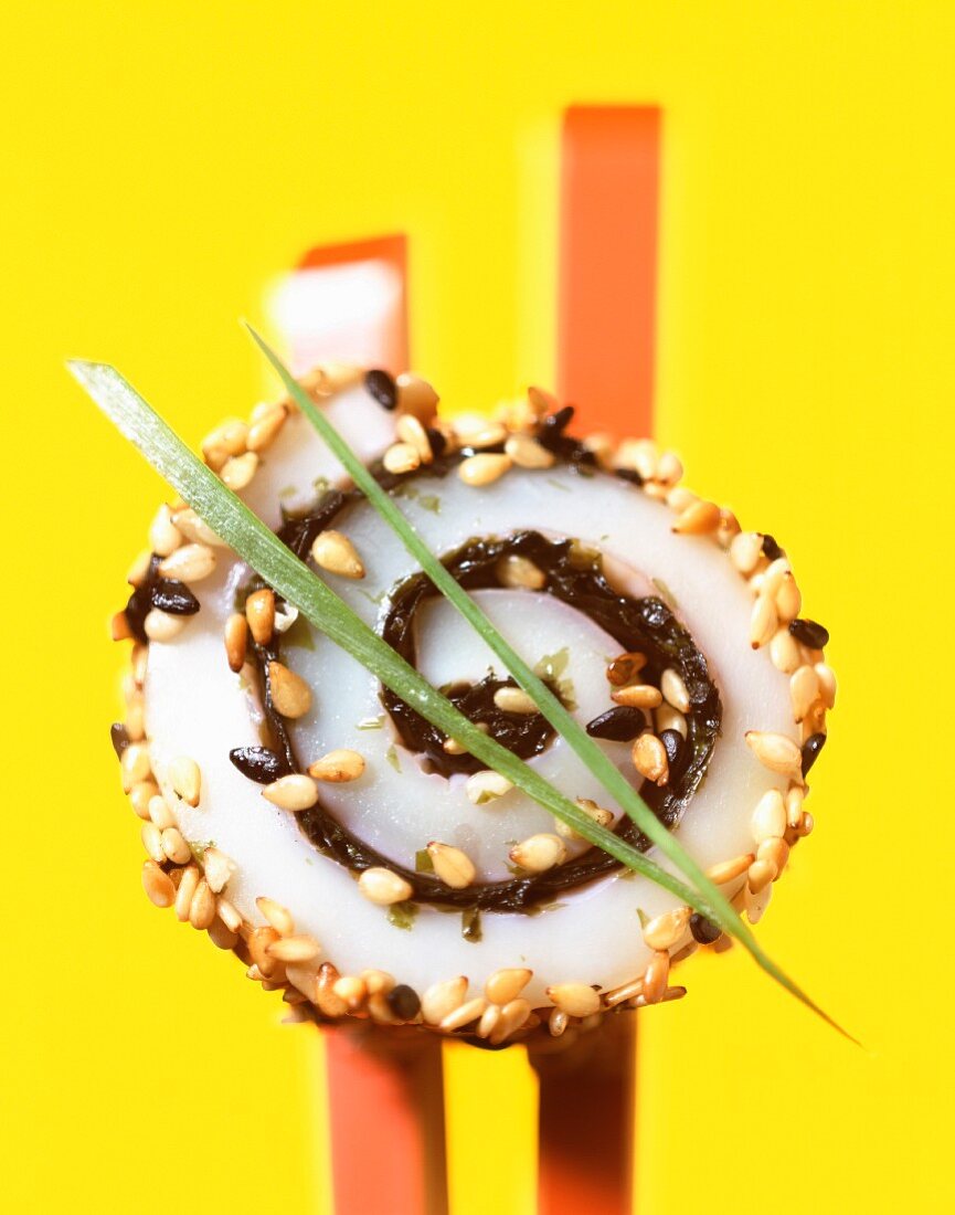 Tintenfisch-Sushi mit Essstäbchen vor gelbem Hintergrund