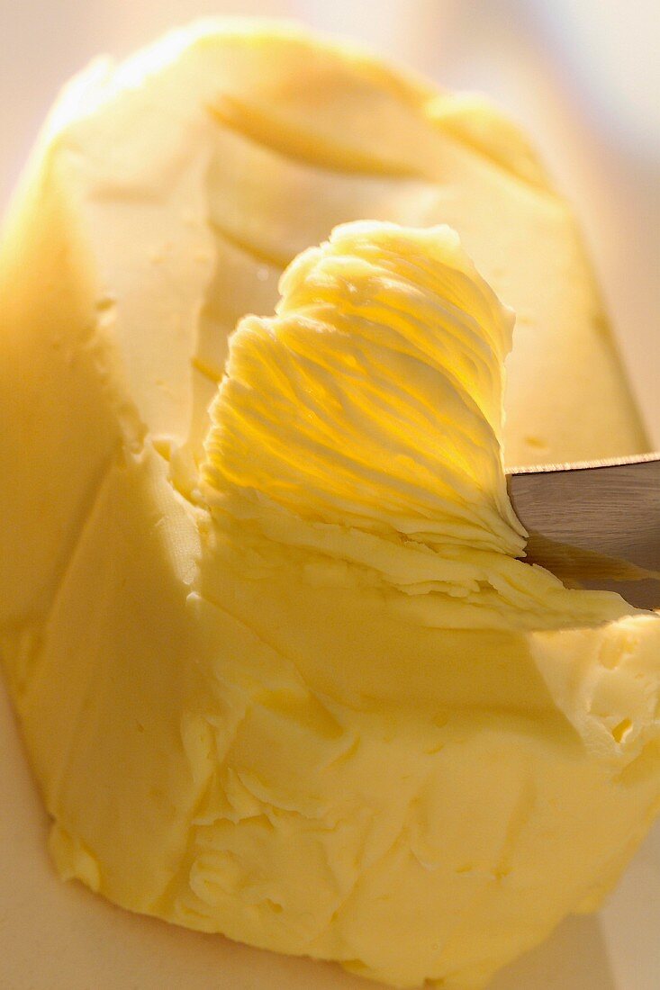 Messer schabt Butter vom Stück ab
