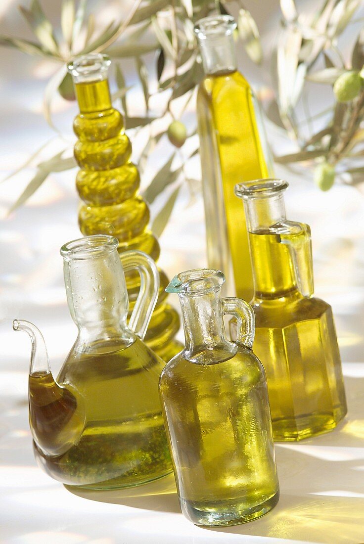 Verschiedene Glasflaschen und Kännchen mit Olivenöl