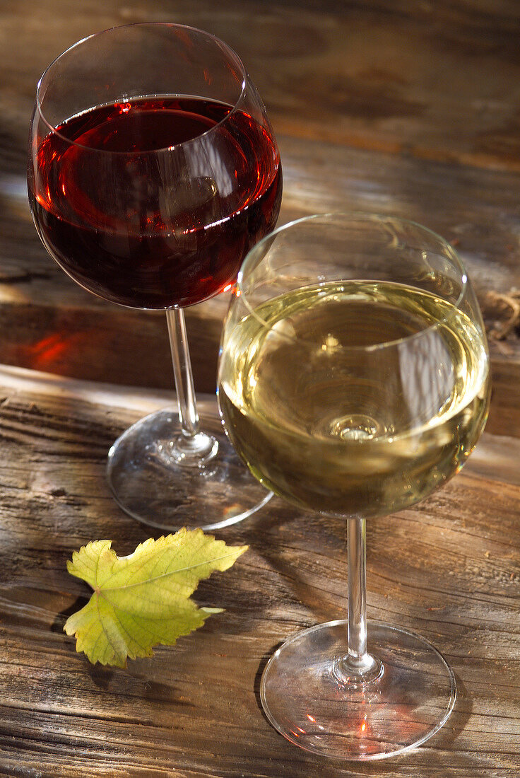 Je ein Glas Rot- und Weißwein auf Holzuntergrund