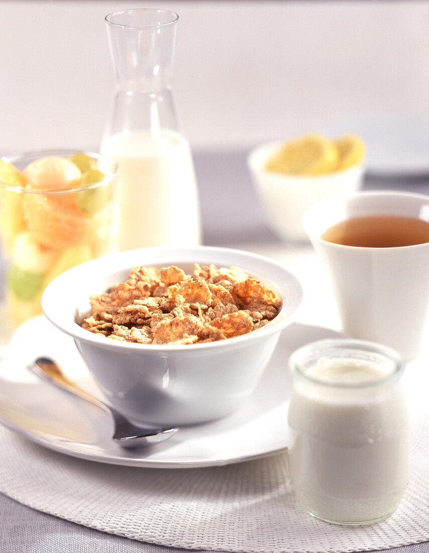 Frühstück mit Cornflakes in einer Schale, Jogurt und Tee
