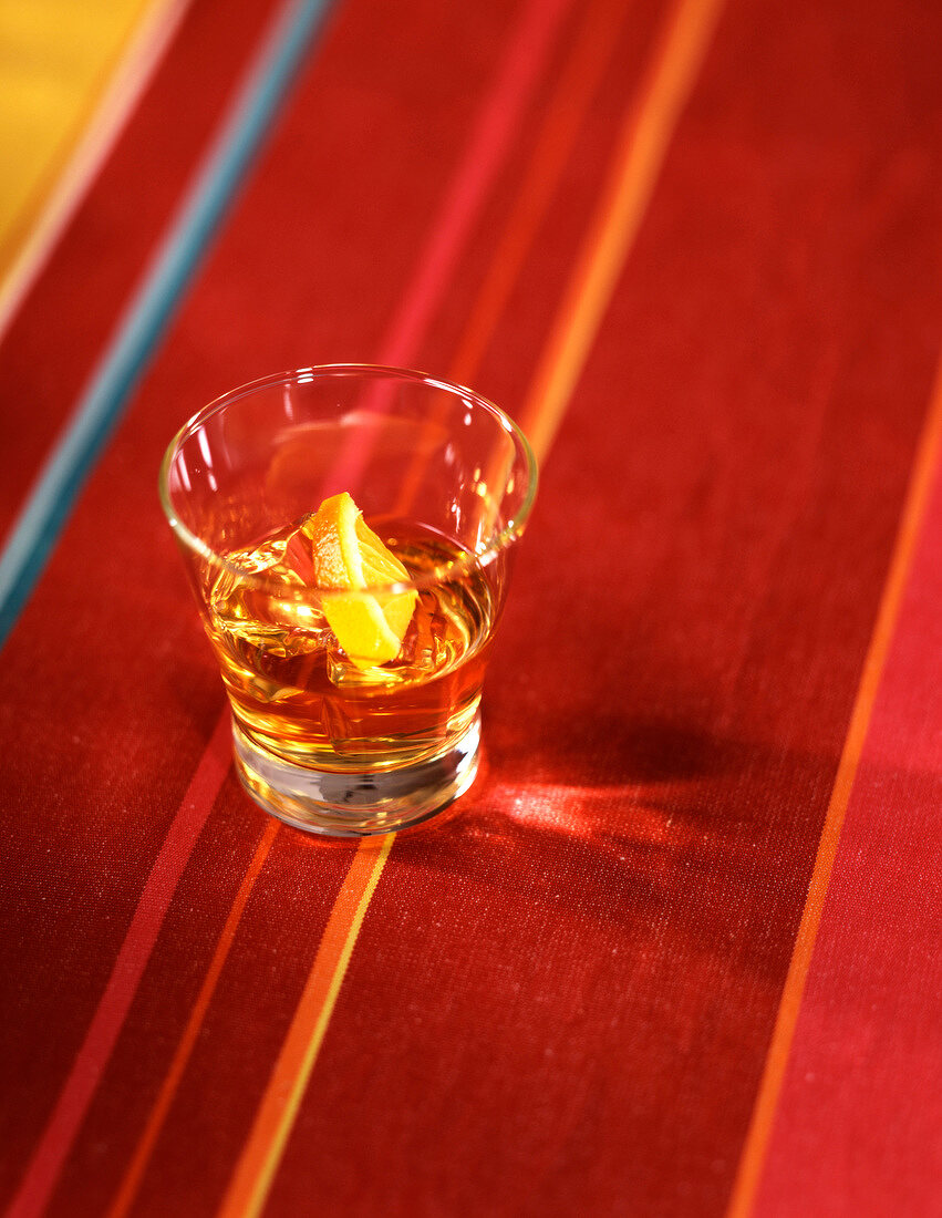 Ein Glas Whisky auf einem rotem Tischtuch mit bunten Streifen