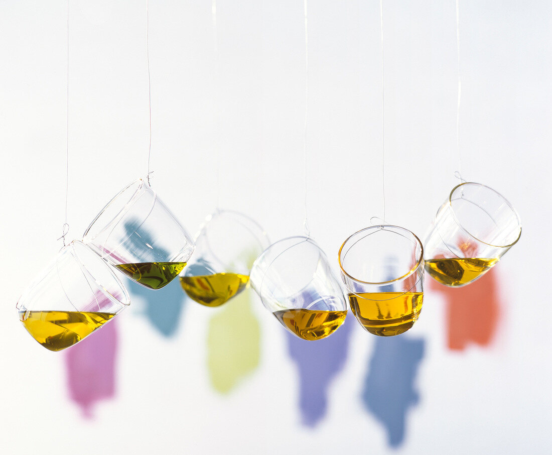 An Schnüren hängende Glasbecher mit verschiedenen Ölen