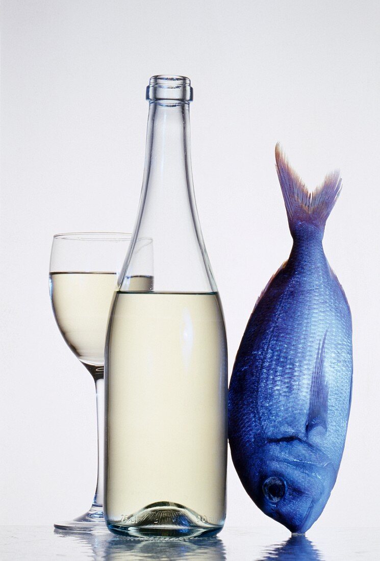 Weissweinglas und Flasche neben einem Fisch
