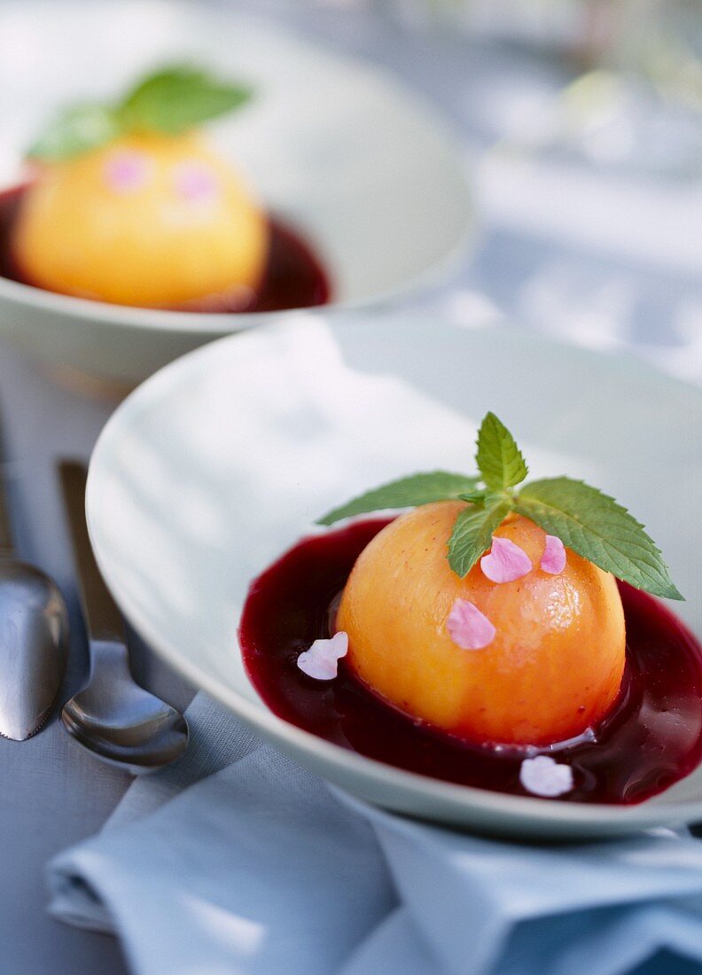 Peaches poached in sweet wine with blackcurrant sauce