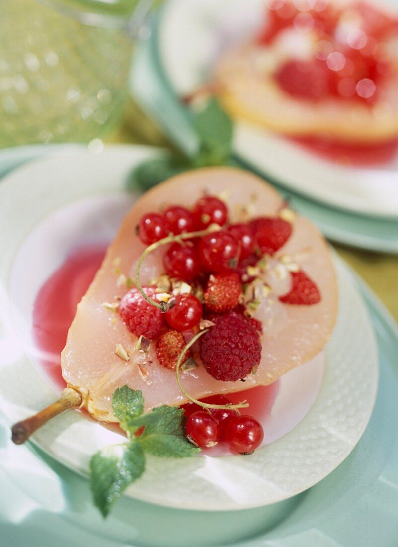 Poached pears stuffed with summer fruit and summer fruit coulis