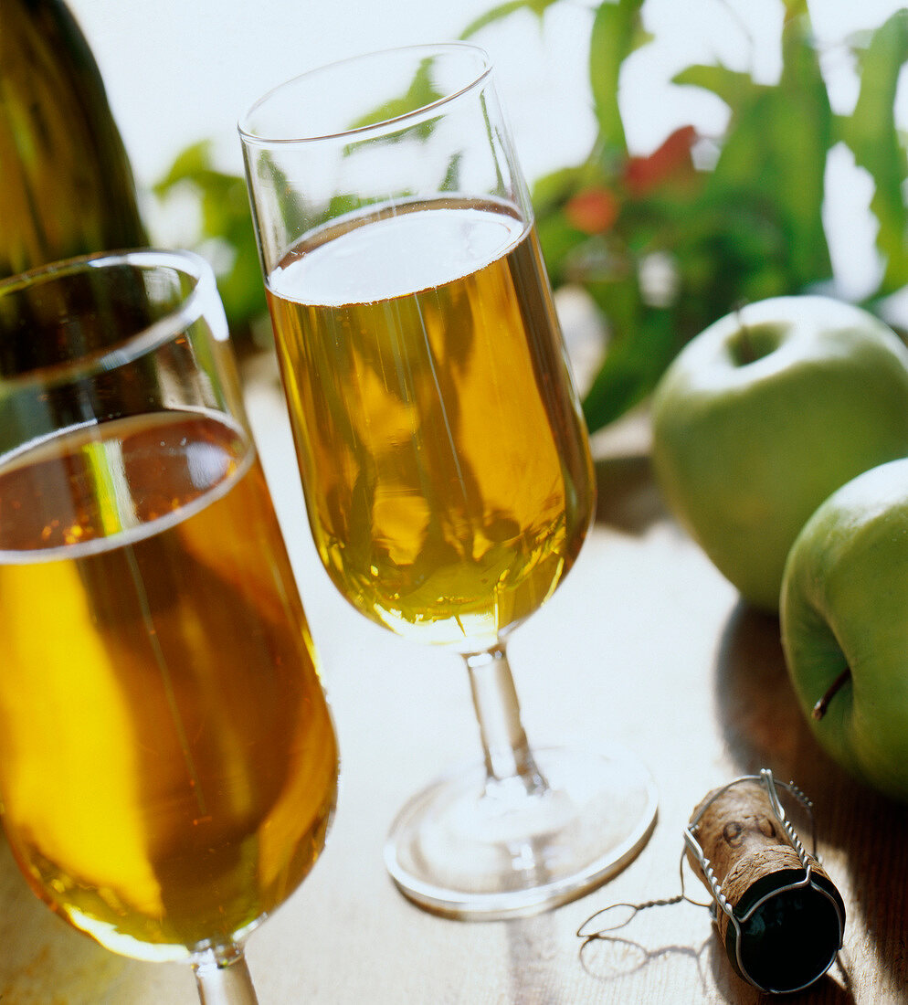 Zwei Gläser Cidre mit Flasche und grünen Äpfeln
