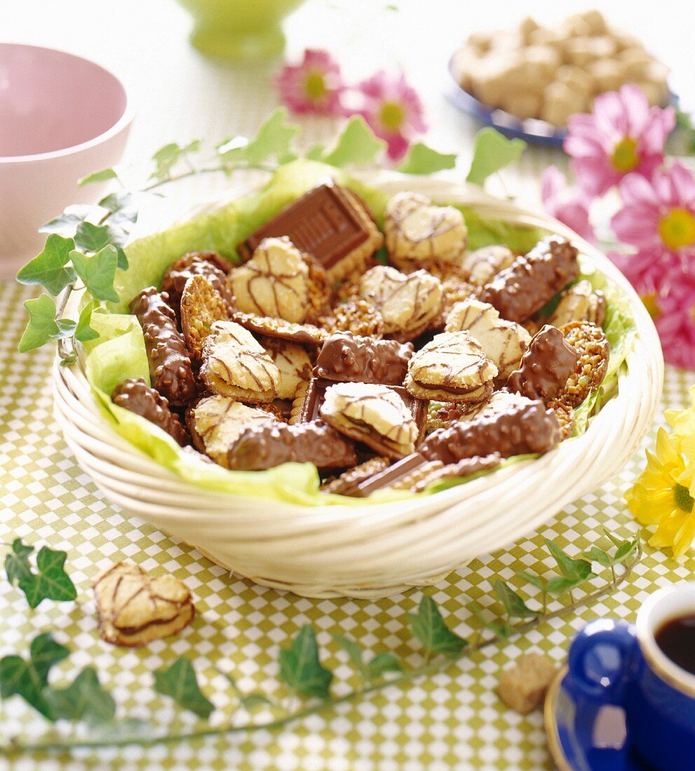 Gemischte Schokoladenkekse in einem Weidenkorb mit Blütendeko