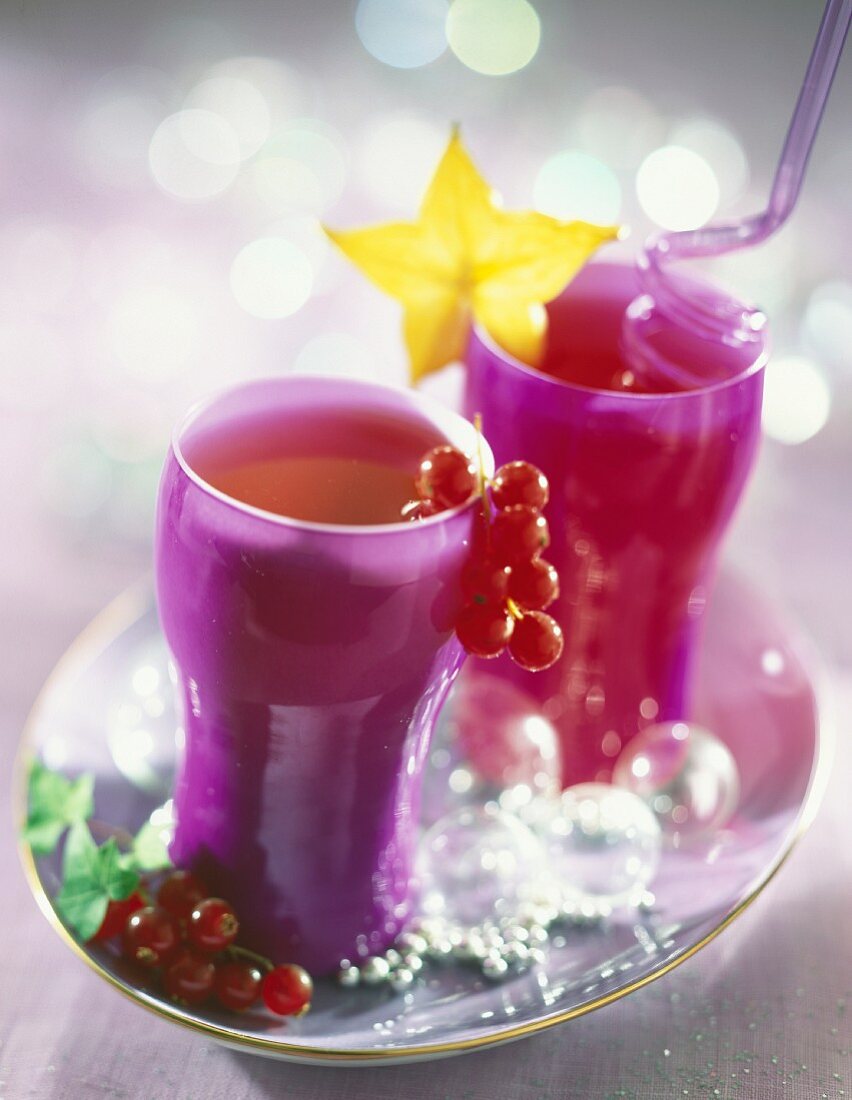 Pinke Gläser mit Trauben-Apfel-Himbeer-Saft auf weihnachtlichem Tisch