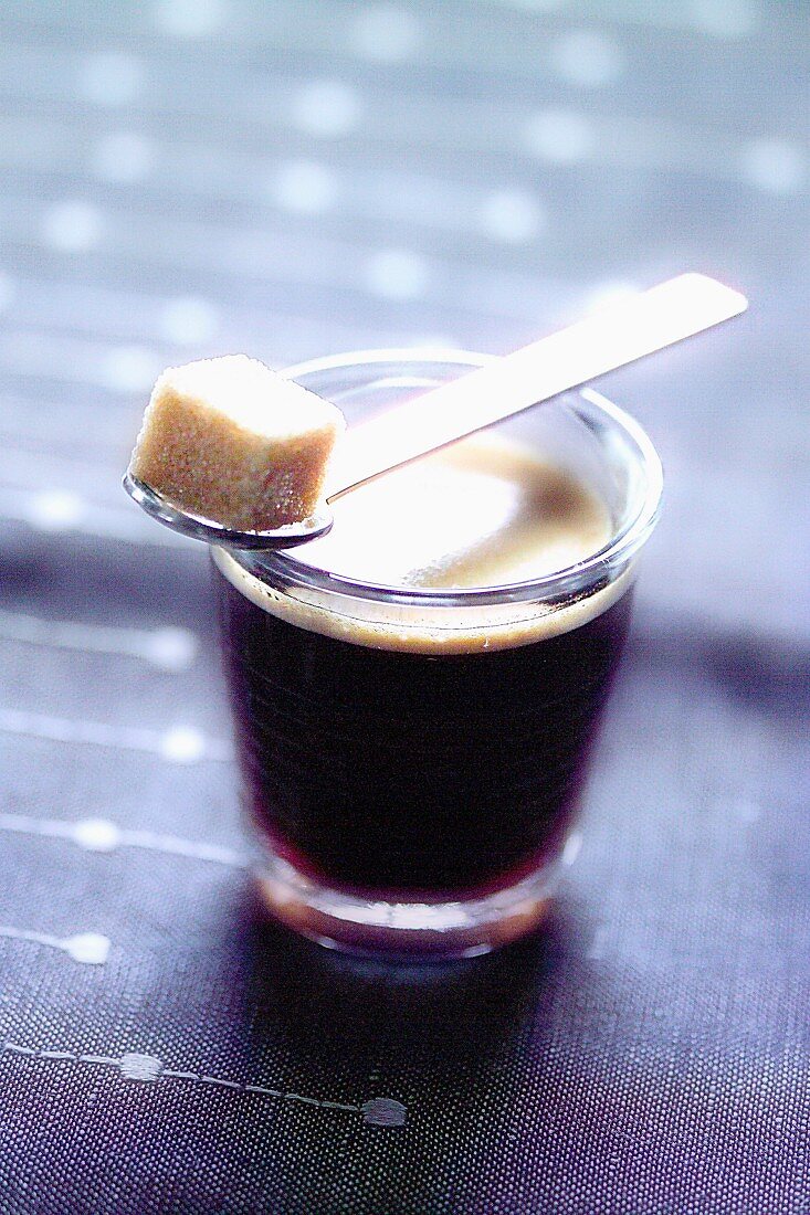 Schwarzer Kaffee in Glastasse mit Zuckerwürfel