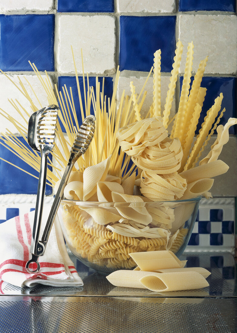 Getrocknete Pasta in einer Glasschüssel mit Nudelzange