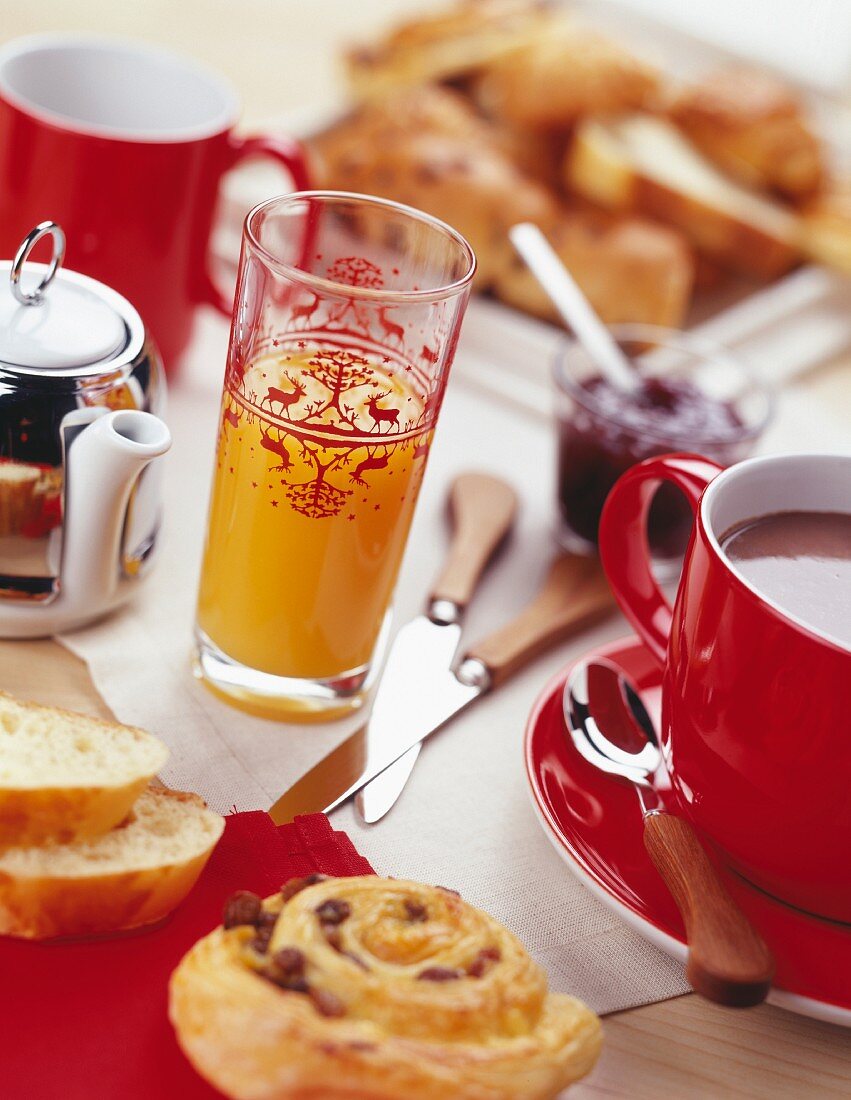 Frühstückstisch mit Orangensaft, Kaffee und Gebäck