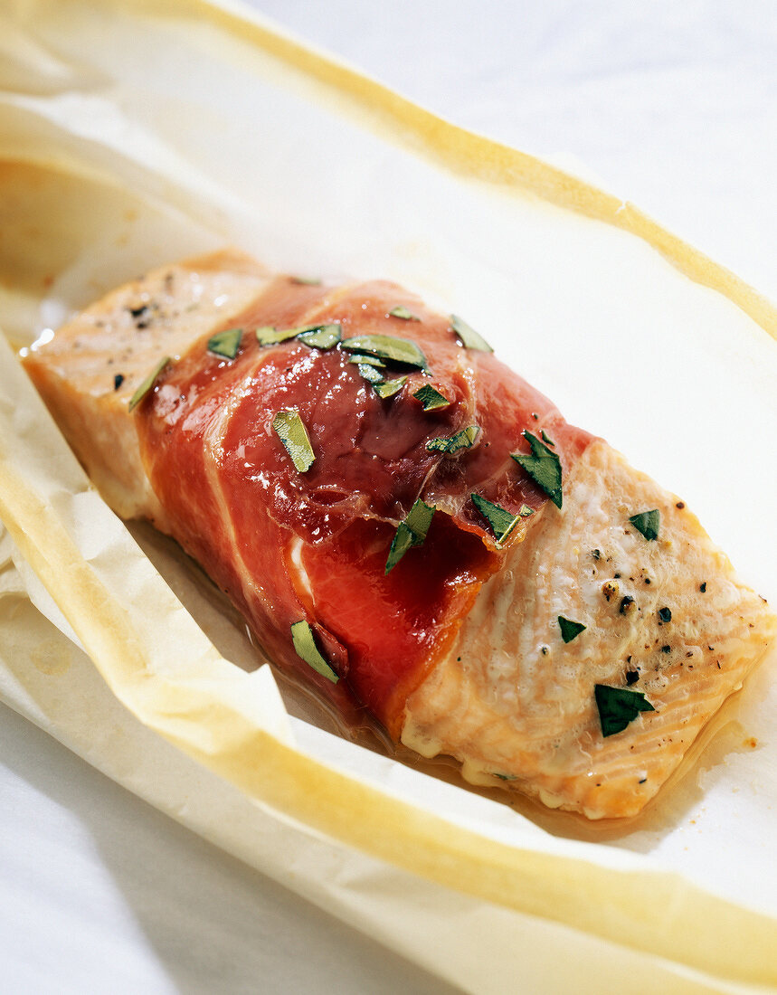 Piece of salmon wrapped in raw ham
