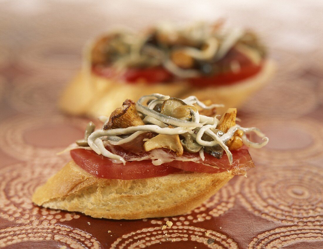 Tomate, Rohschinken und Pilze auf Weissbrotscheiben