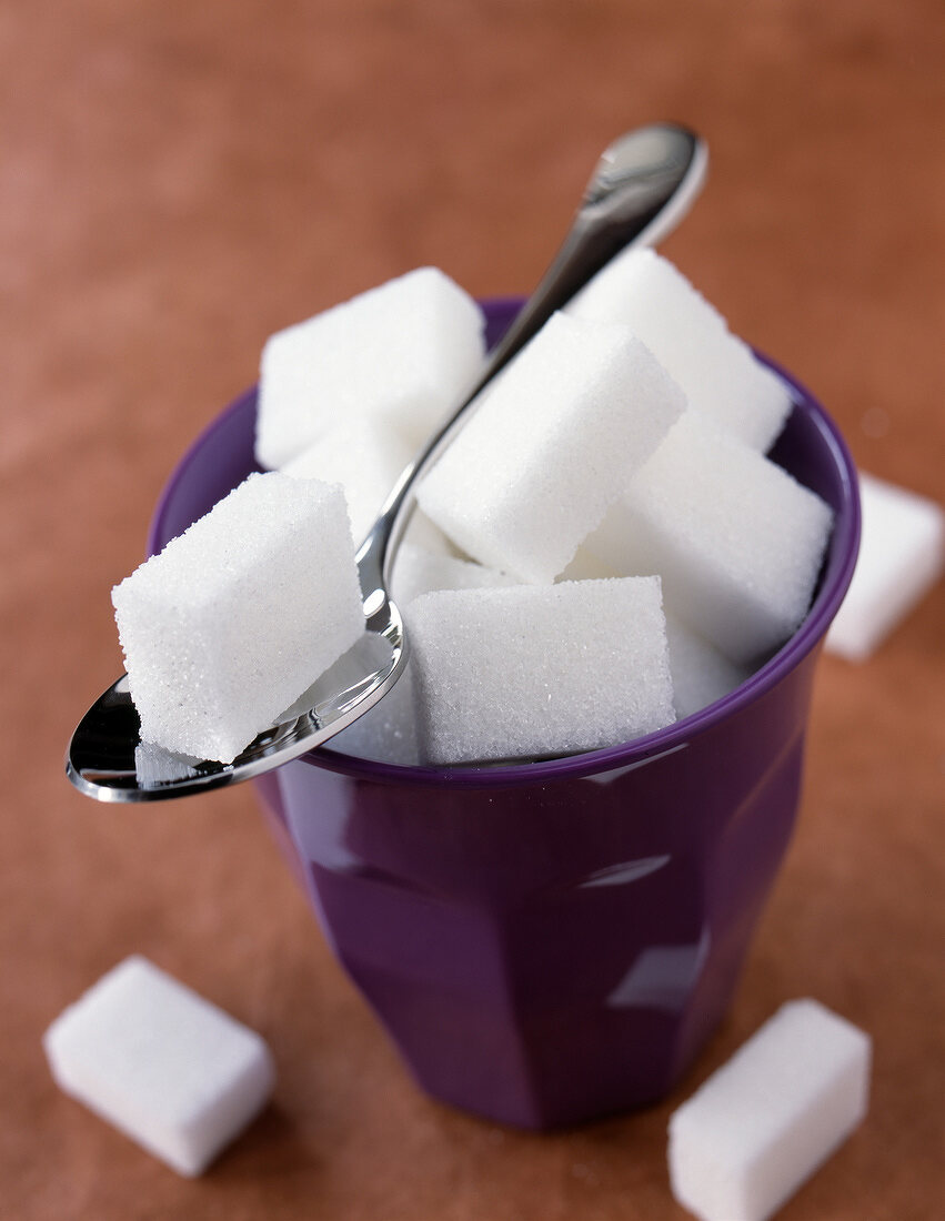 Becher mit Würfelzucker und einem Löffel