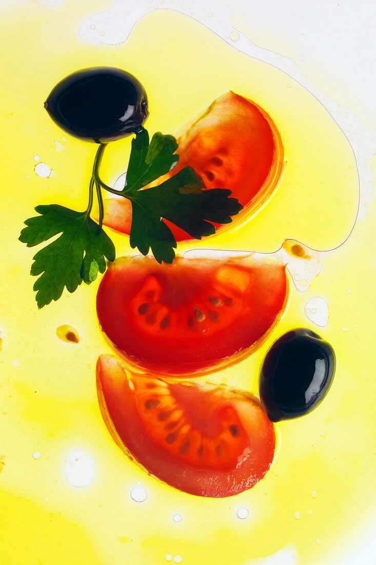 Tomatenscheiben, Oliven und Petersilie in Olivenöl