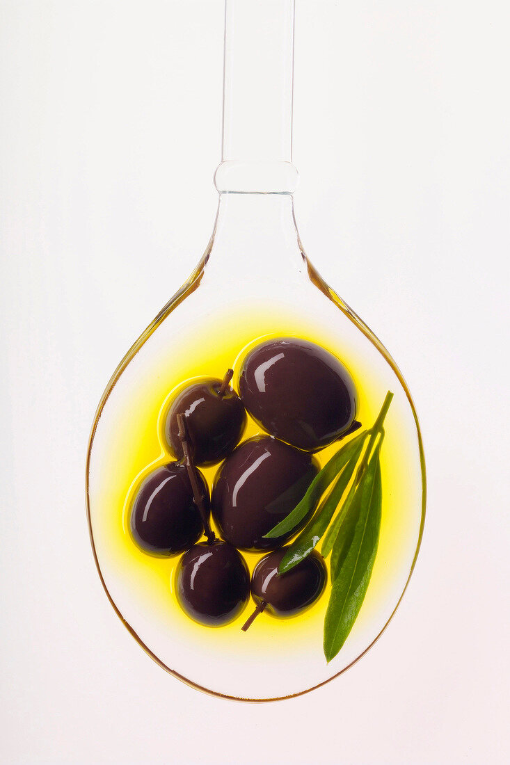 Oliven im Olivenöl auf durchsichtigem Löffel