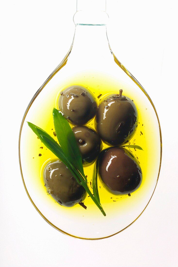 Grüne Oliven auf Löffel in Olivenöl