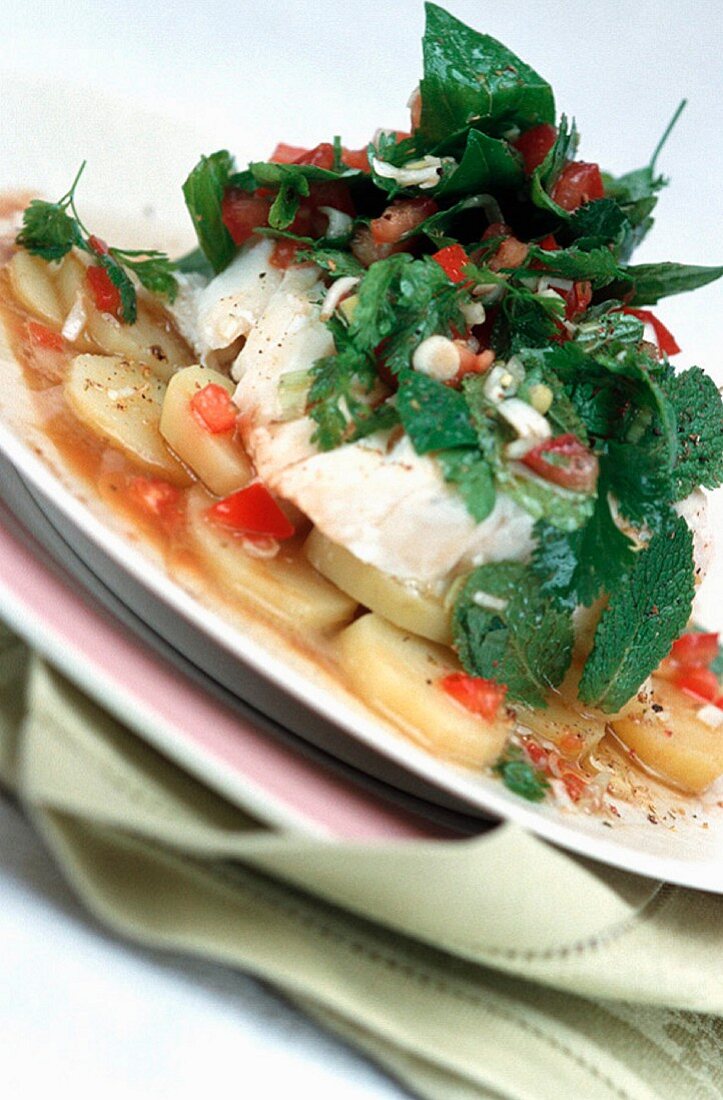 Cod with fresh herbs on a potato and tomato medley
