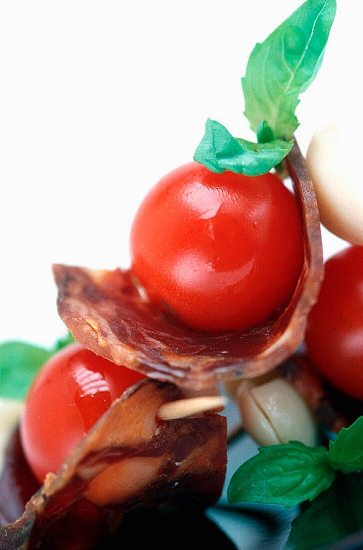 A tomato snack with bacon and basil