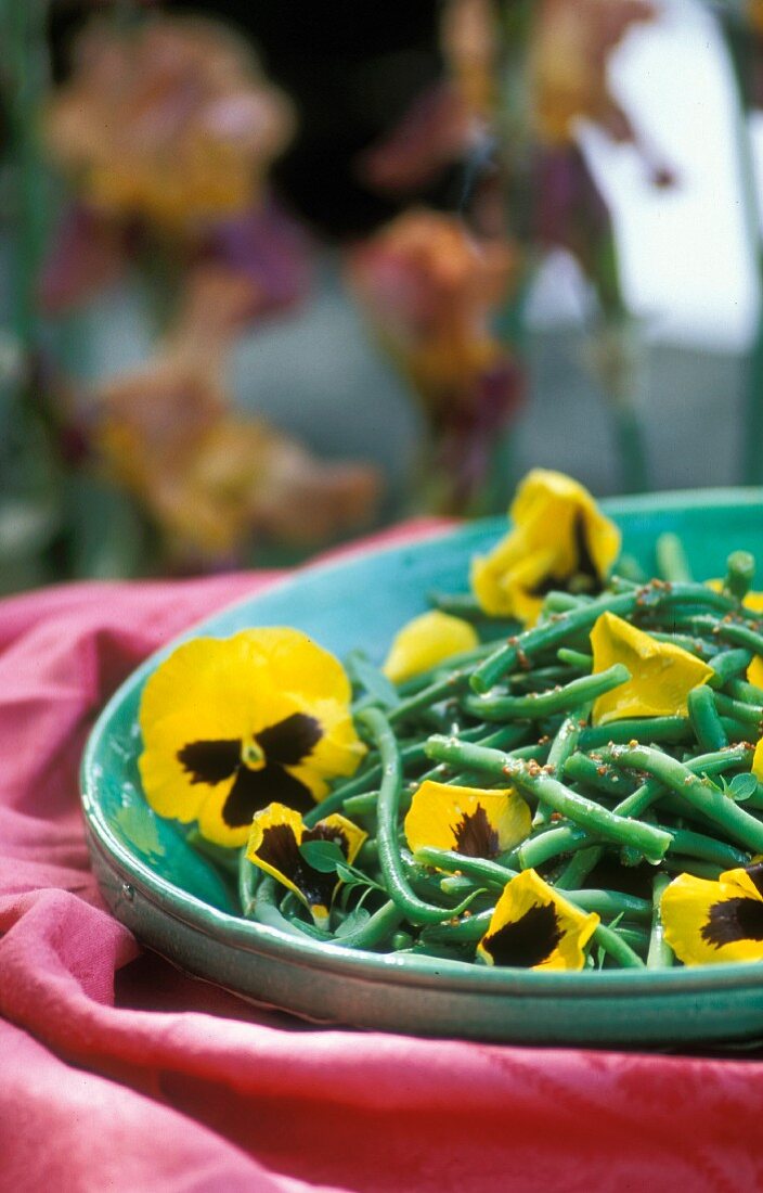 Green beans with pansies on a green plate