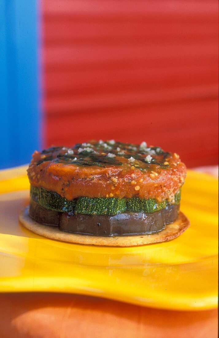 A Provencal-style vegetable tartlet with aubergines, courgettes, tomatoes and basil on a Parmesan crackers