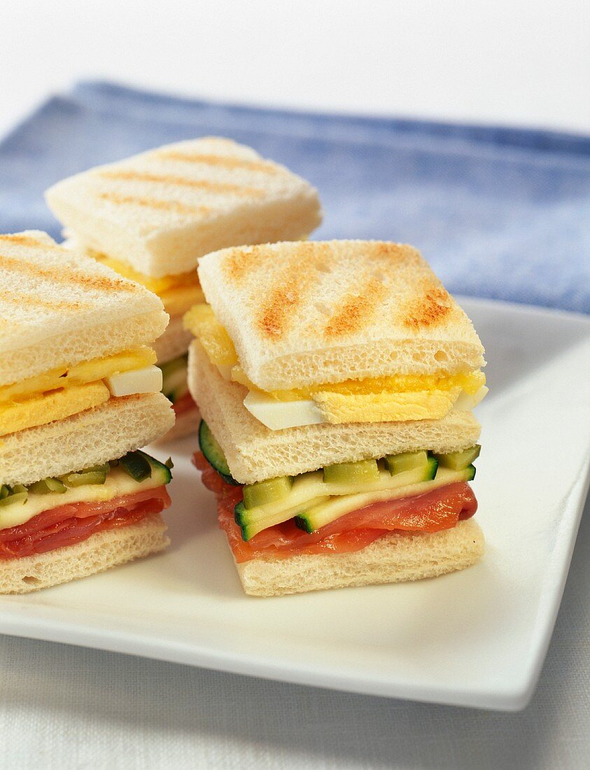 Small toasted sandwiches with salmon,cucumber and hard boiled egg