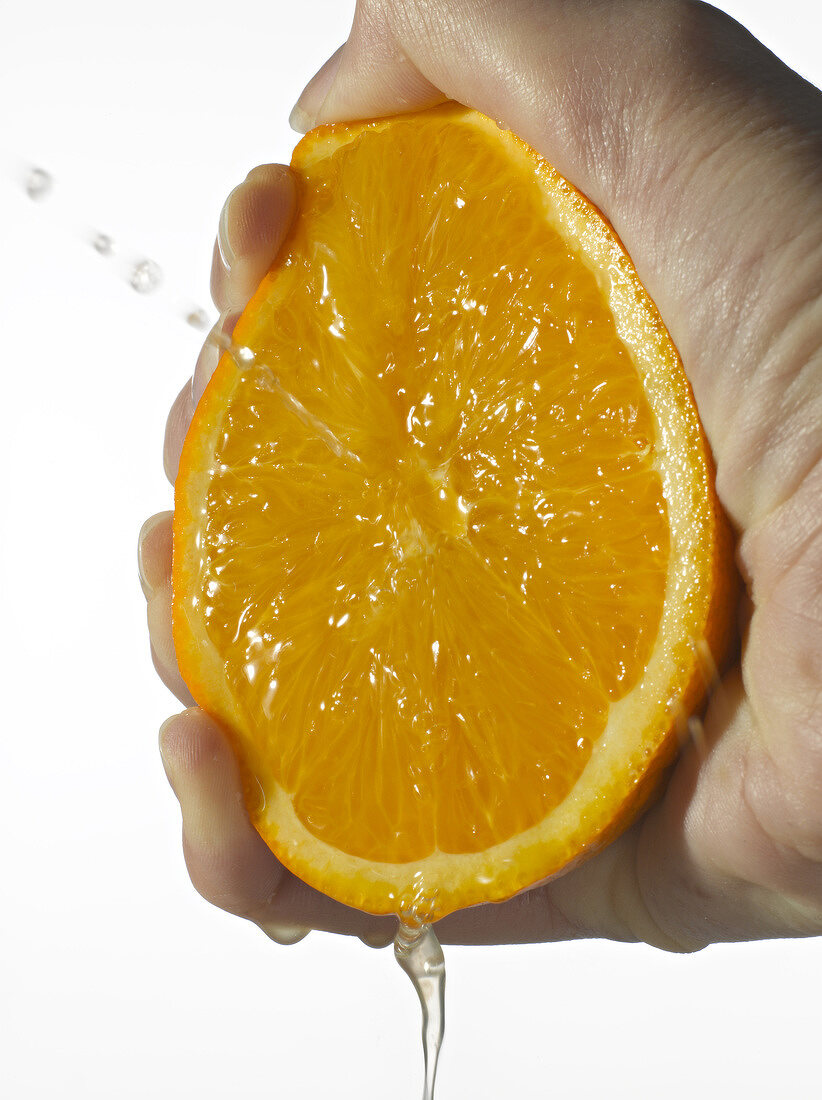 Orangenhälfte wird mit der Hand ausgedrückt