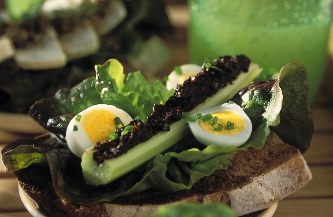 Celery filled with tapenade, quail's eggs and lettuce leaves on grilled bread