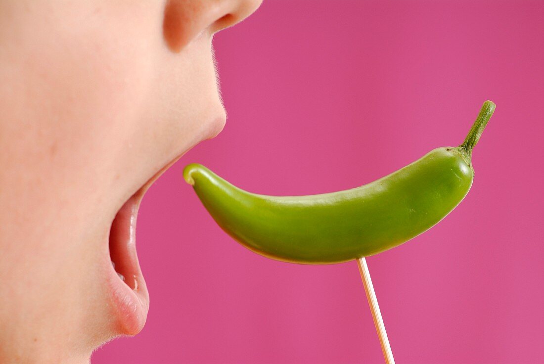 Child biting a small green pepper