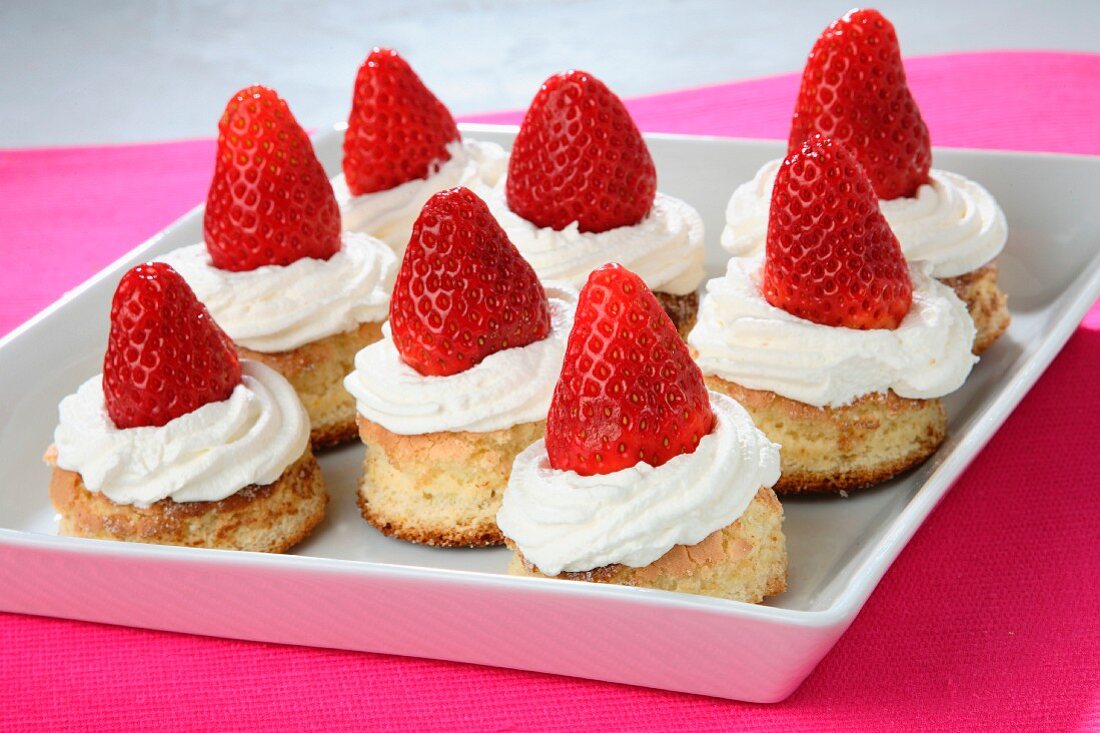 Cookies topped with cream and strawberries