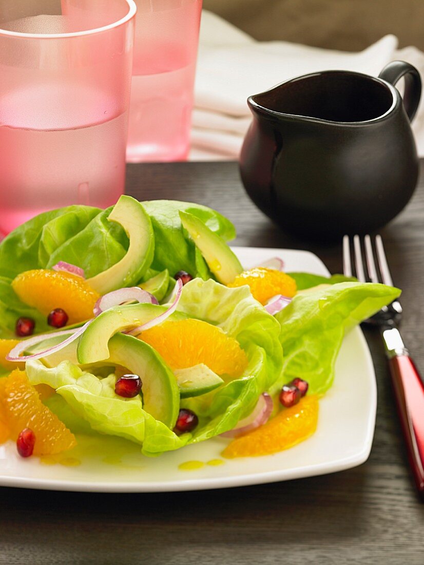 A green salad with avocado, oranges and pomegranate seeds