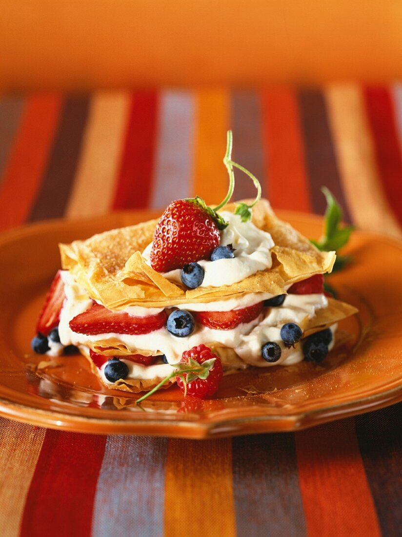 Layered cake made from filo pastry with cream and fruits of the forest