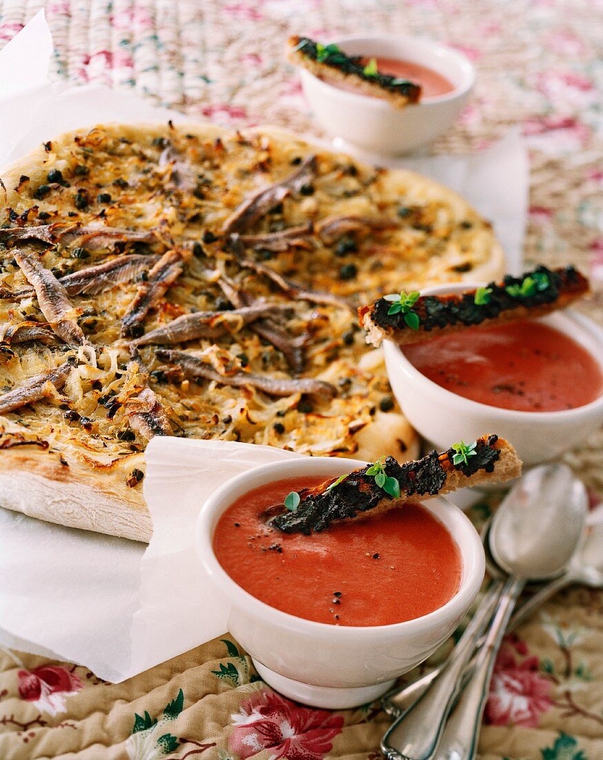 Pissaladière (Zwiebelkuchen mit Sardellenfilets und Oliven, Frankreich) und Tomatensuppe mit Tapenade-Brotstangen