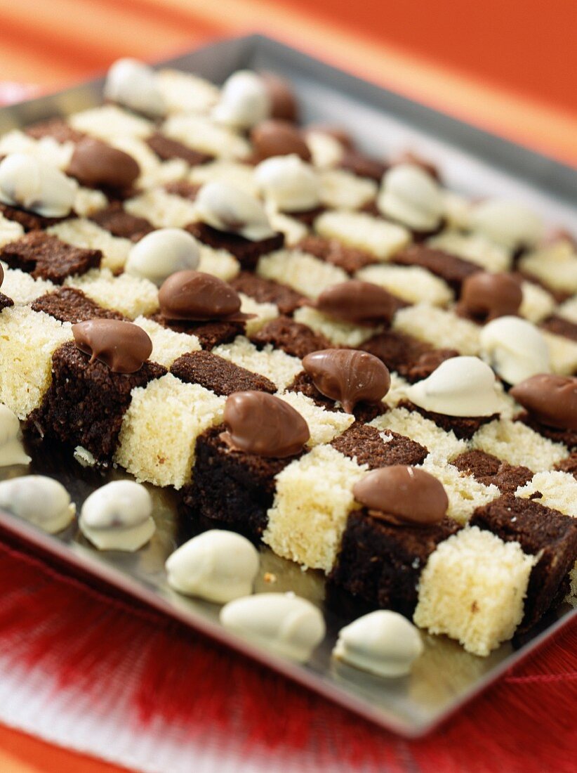 Chessboard cake (sponge cake with chocolate and yoghurt) with chocolate coated almonds