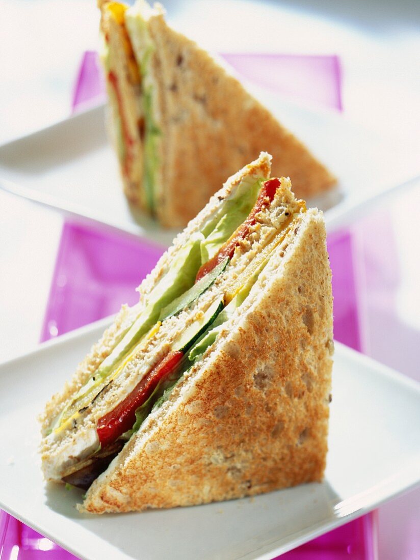 A club sandwich with peppers, lettuce and cheese