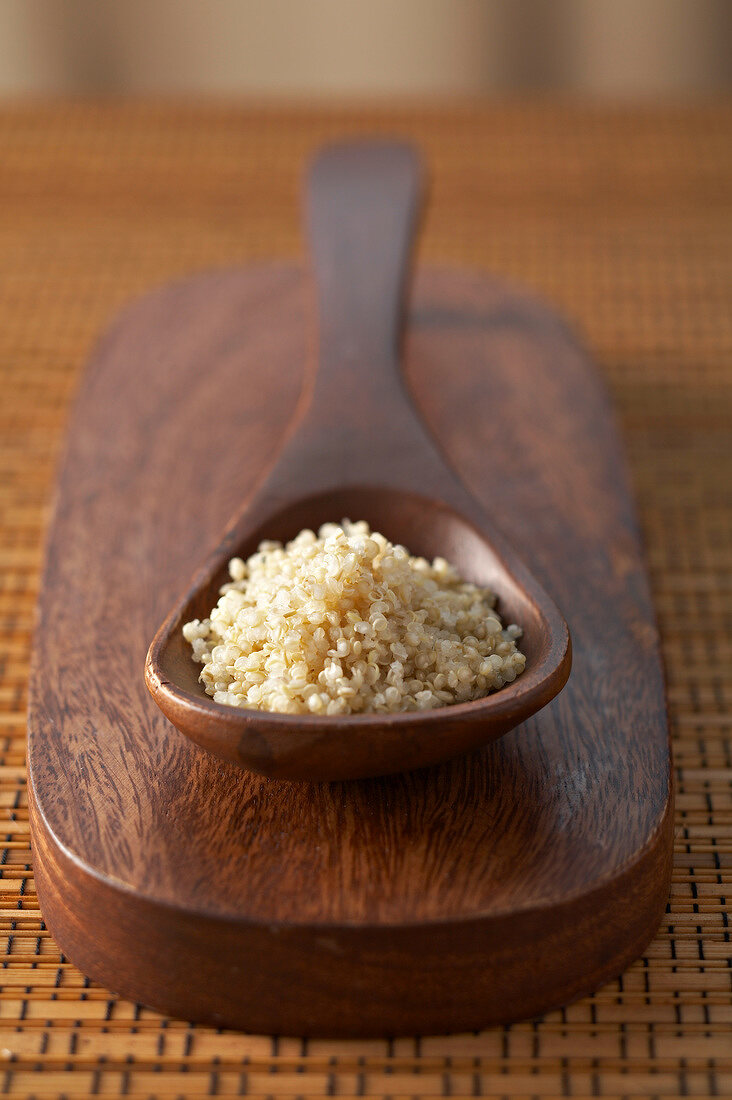 Holzlöffel mit Quinoa auf einem Holzbrett