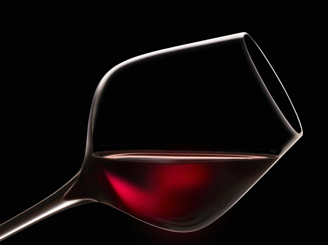 Schräg haltendes Glas Rotwein zur Degustation