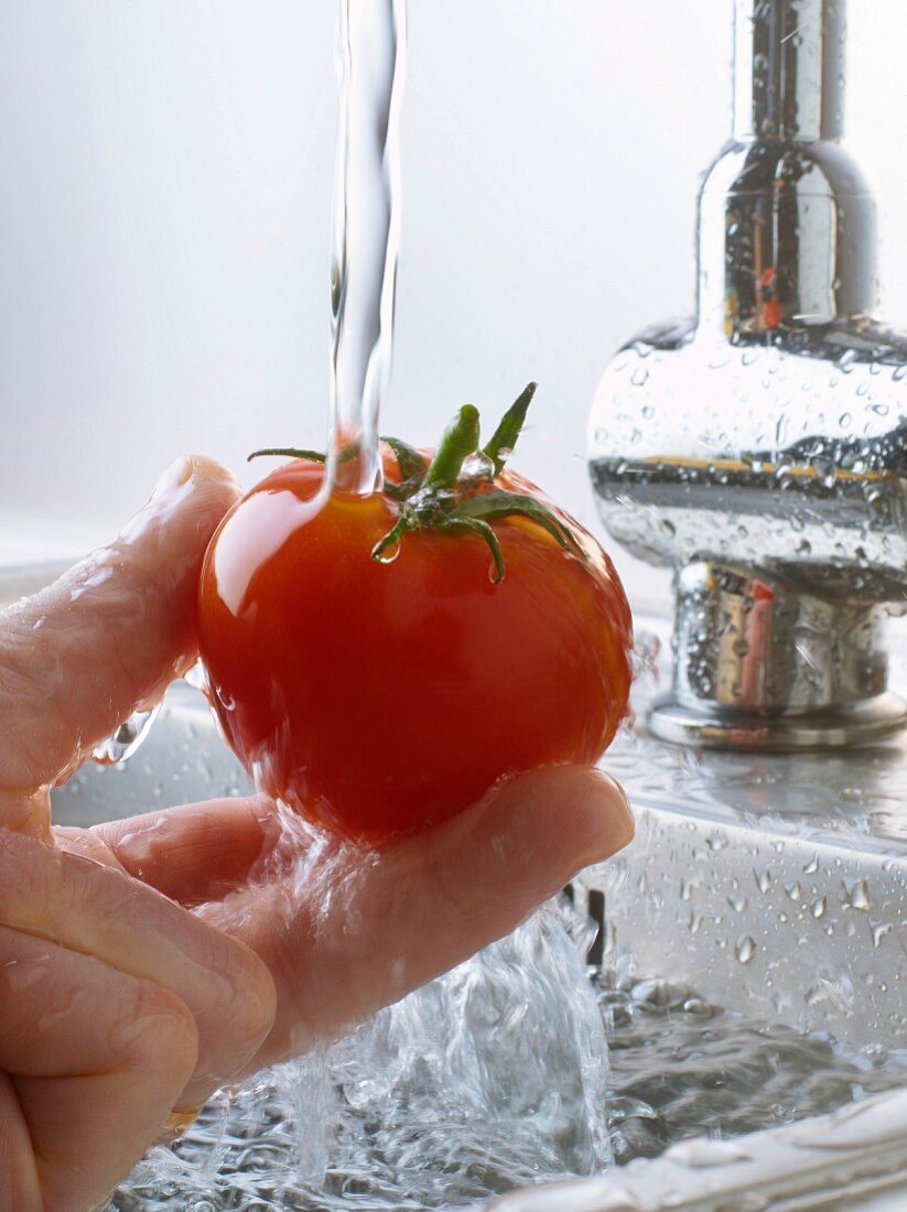 Rinsing a tomato under the tap water