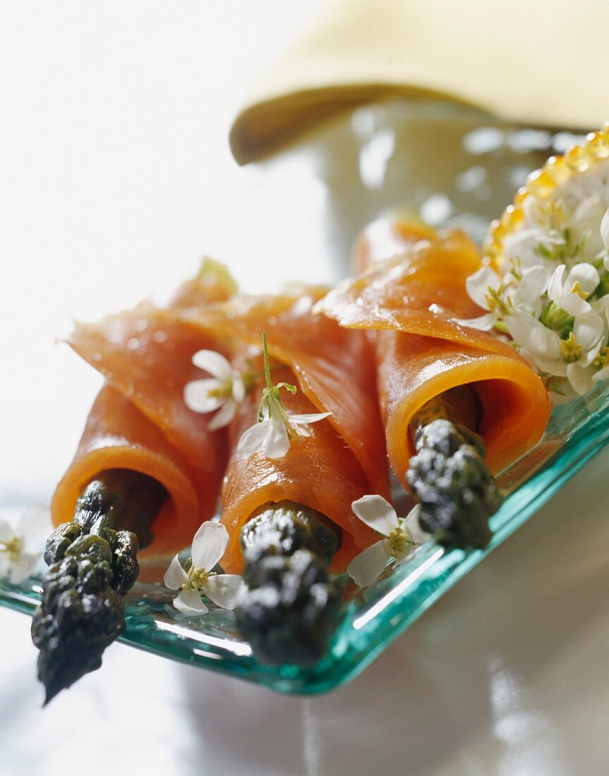 Green asparagus wrapped in sliced smoked salmon and garlic flowers