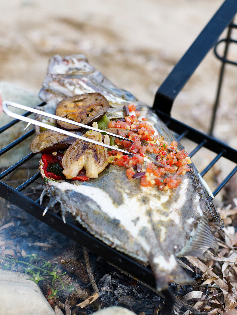 Grilling a fish and vegetables on the beach