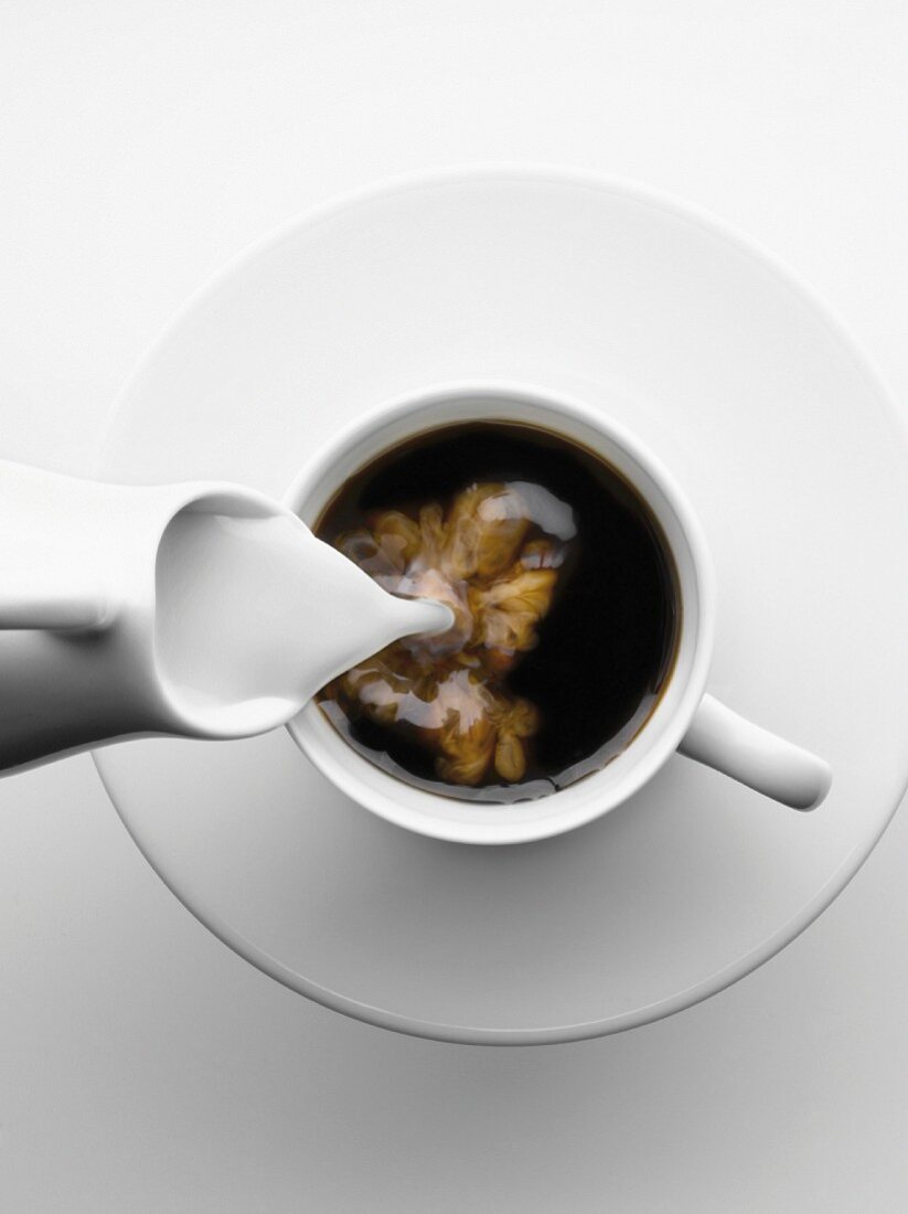 Milch in eine Tasse Kaffee gießen