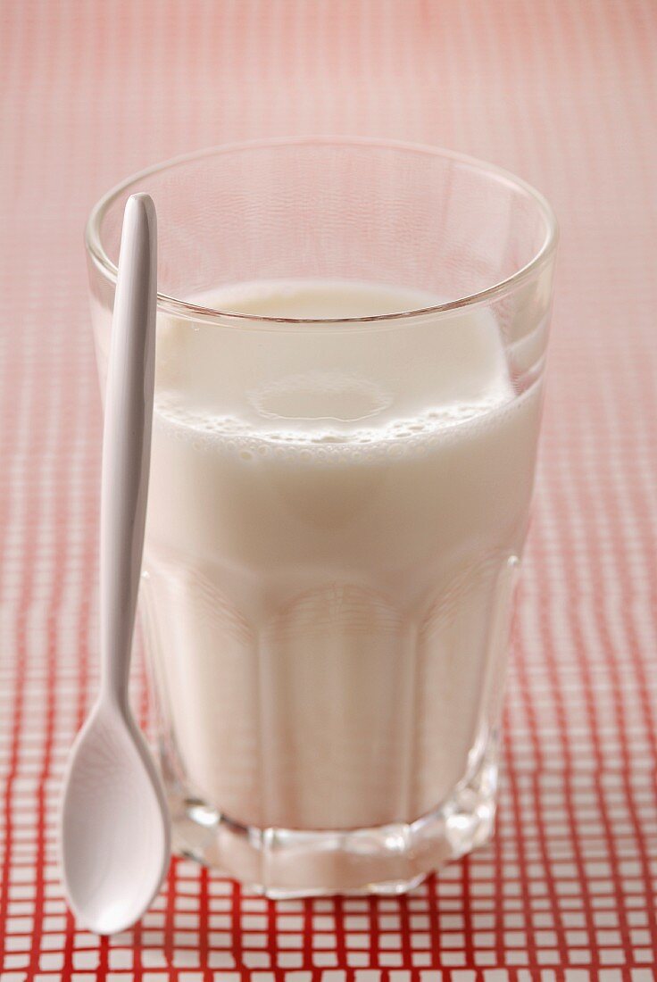 Ein Glas Milch und Plastiklöffel