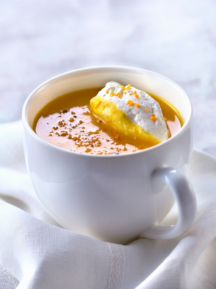 Cream of pumpkin and orange soup with whipped cream and orange zests