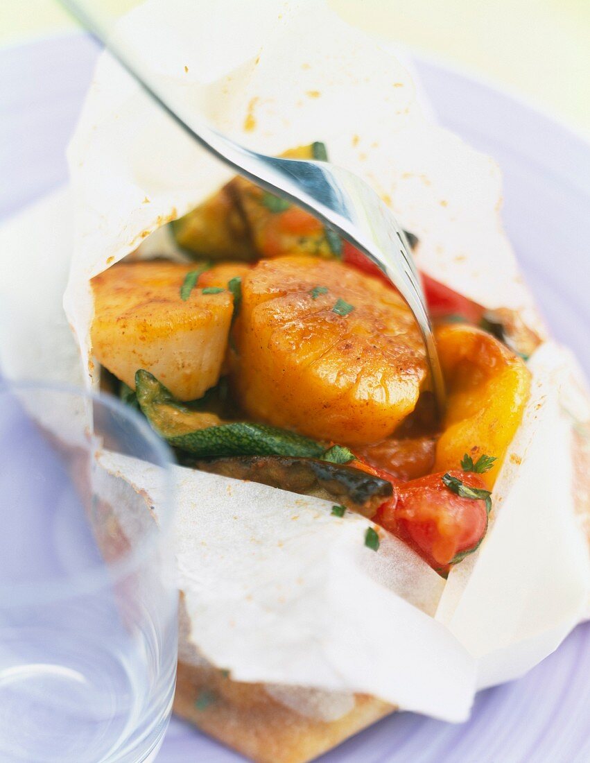 Scallops and vegetables cooked in wax paper